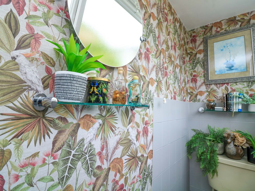 A bathroom with a toilet and shelf with plants and decor at 3 Chantry Hill in Kingsbridge