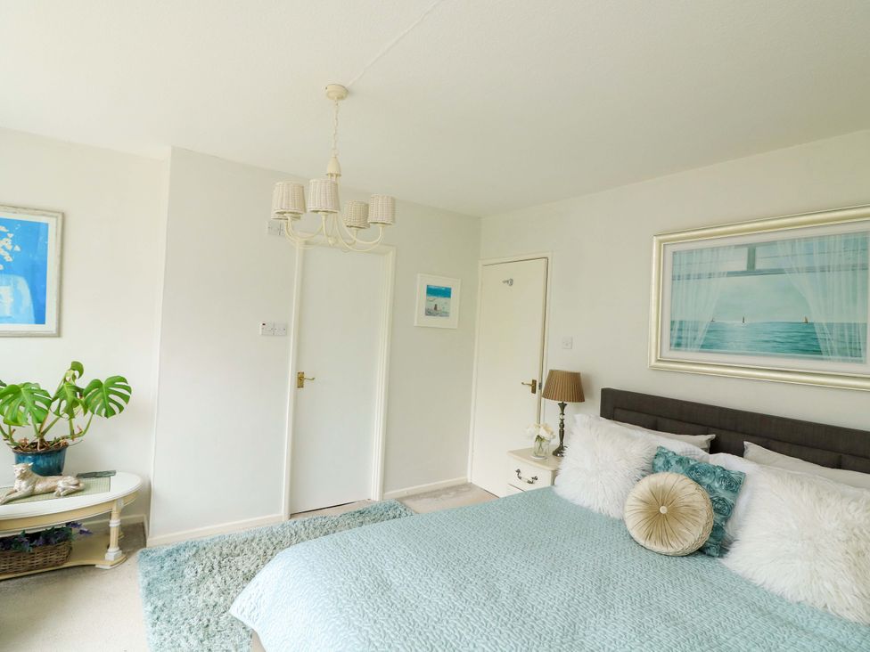 A bedroom with a bed, lamp, and paintings at 3 Chantry Hill, Kingsbridge