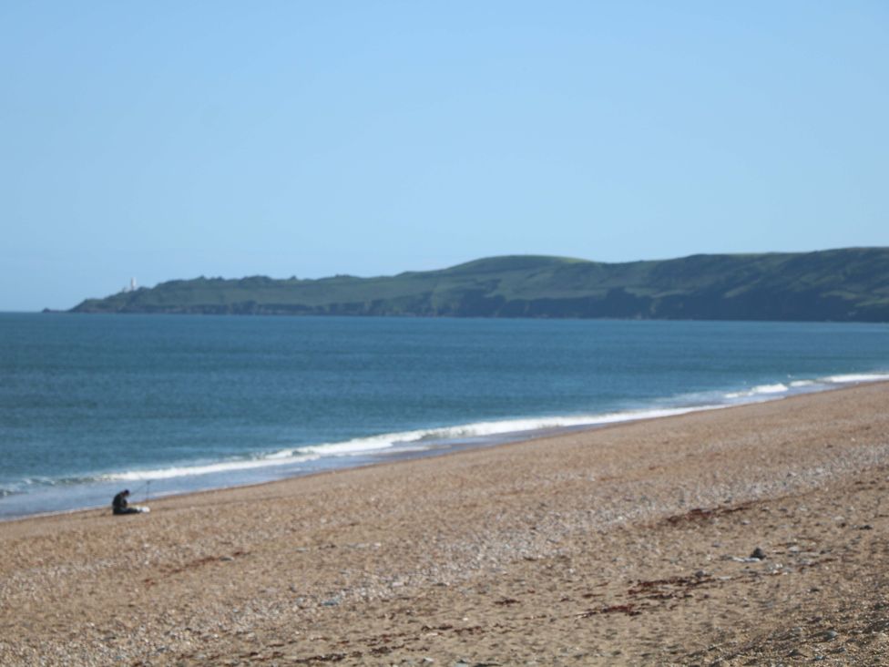 A beach with a person sitting on the sand at 3 Chantry Hill in Kingsbridge