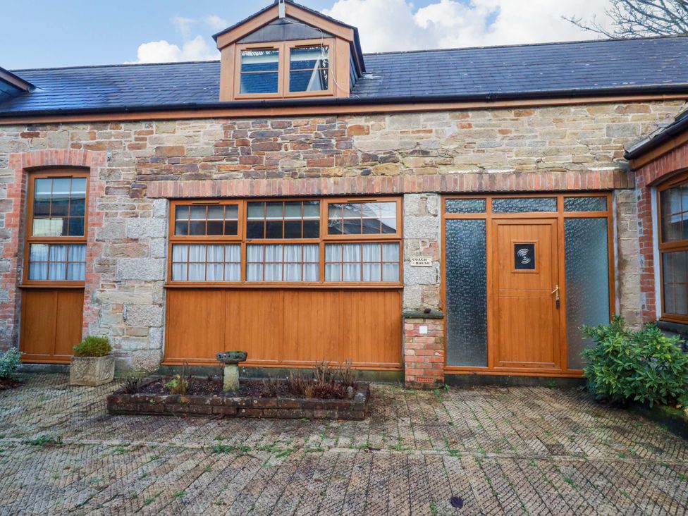 An exterior view of a property with stone walls and wooden features at The Coach House in Falmouth