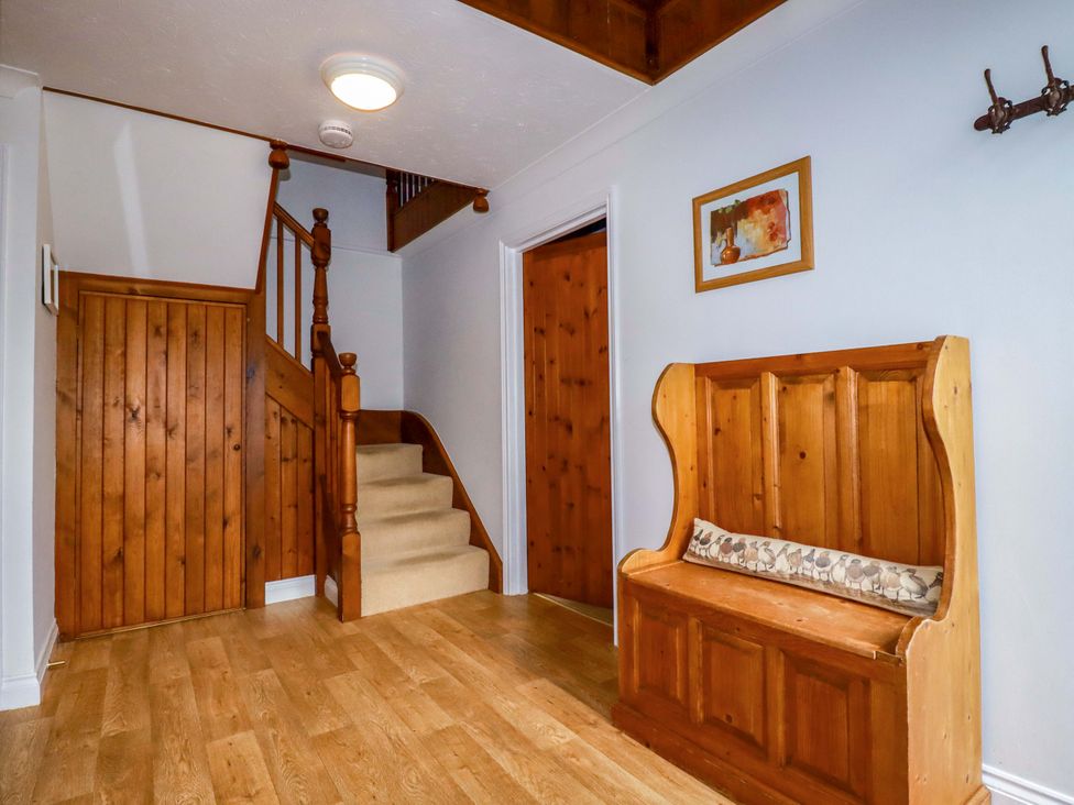 A hallway with a wooden bench and staircase at The Coach House in Falmouth
