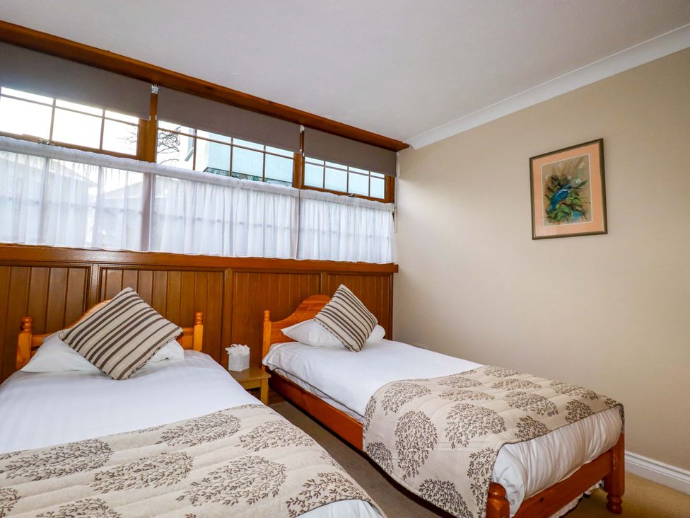 A bedroom with two beds and a picture on the wall at The Coach House in Falmouth