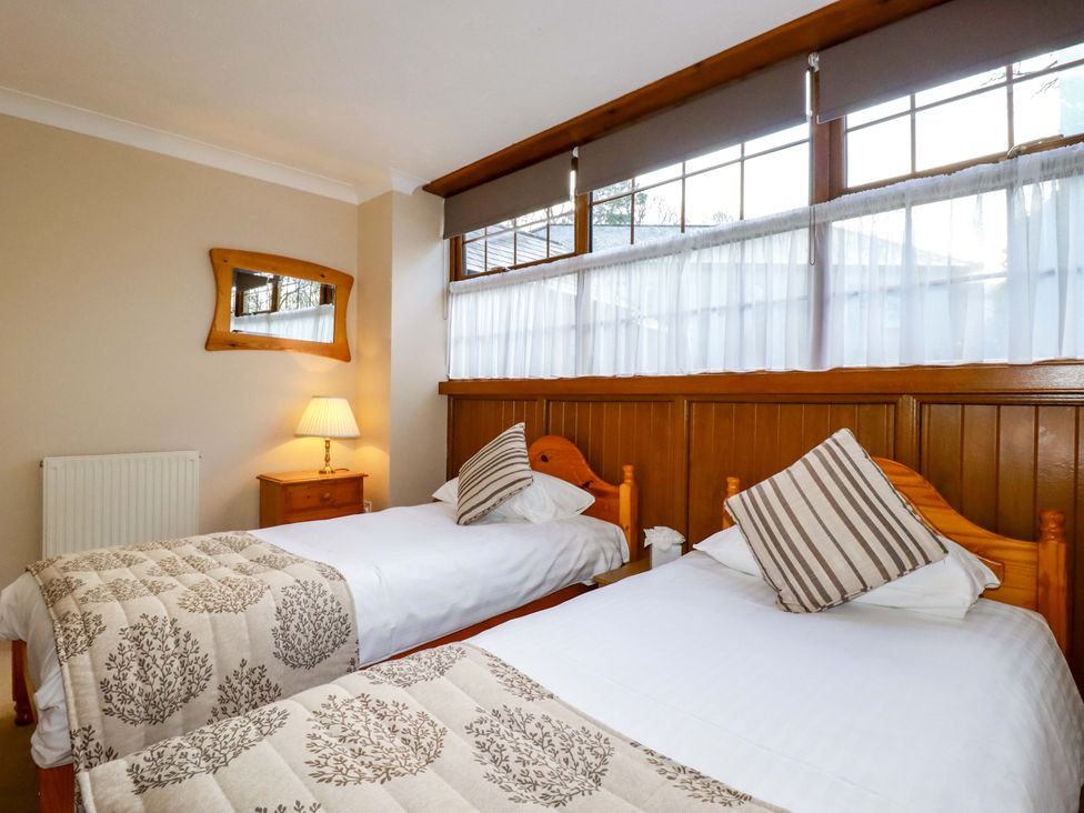 A bedroom with twin beds and a nightstand at The Coach House in Falmouth