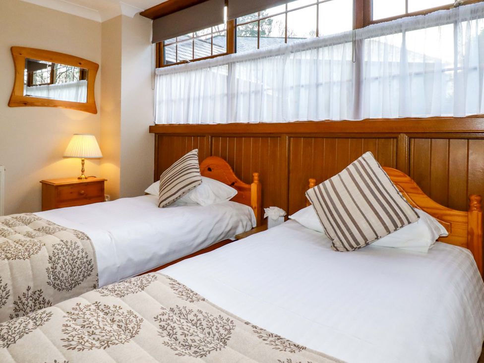 A bedroom with two beds and a lamp at The Coach House in Falmouth
