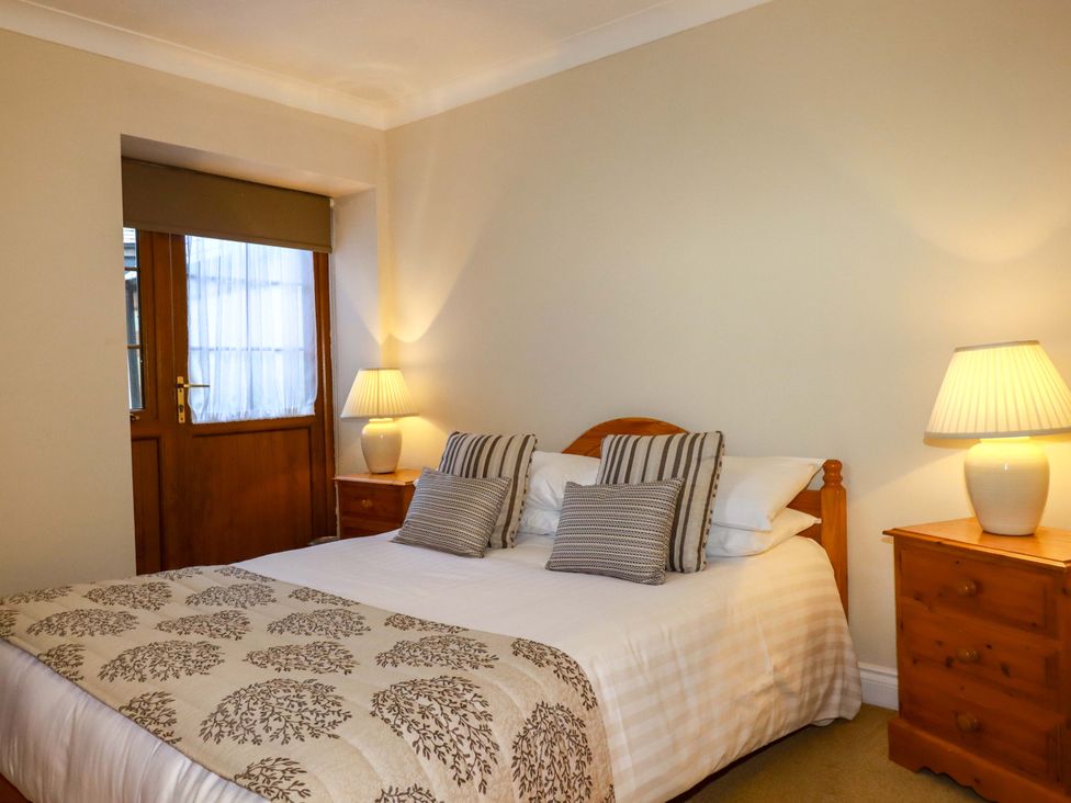 A bedroom with a bed and nightstands at The Coach House in Falmouth