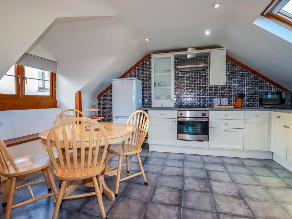 A kitchen with a dining table and chairs at The Coach House in Falmouth
