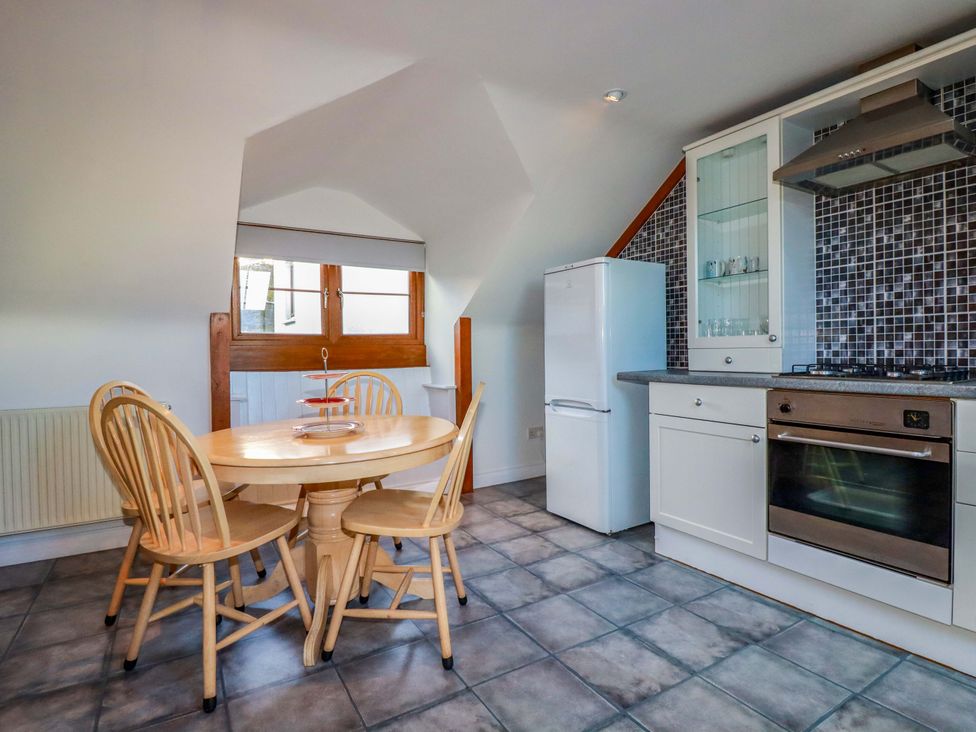 A kitchen with a table and chairs at The Coach House in Falmouth