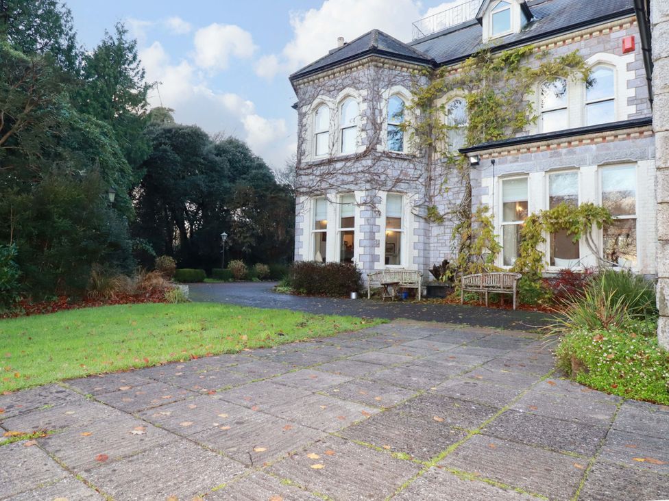 An exterior view of a house with benches and a pathway at The Coach House in Falmouth