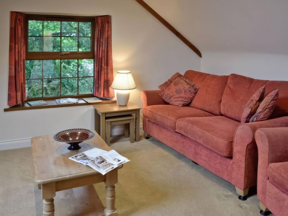 A living room with a couch, table, and lamp at The Coach House in Budock Water near Falmouth