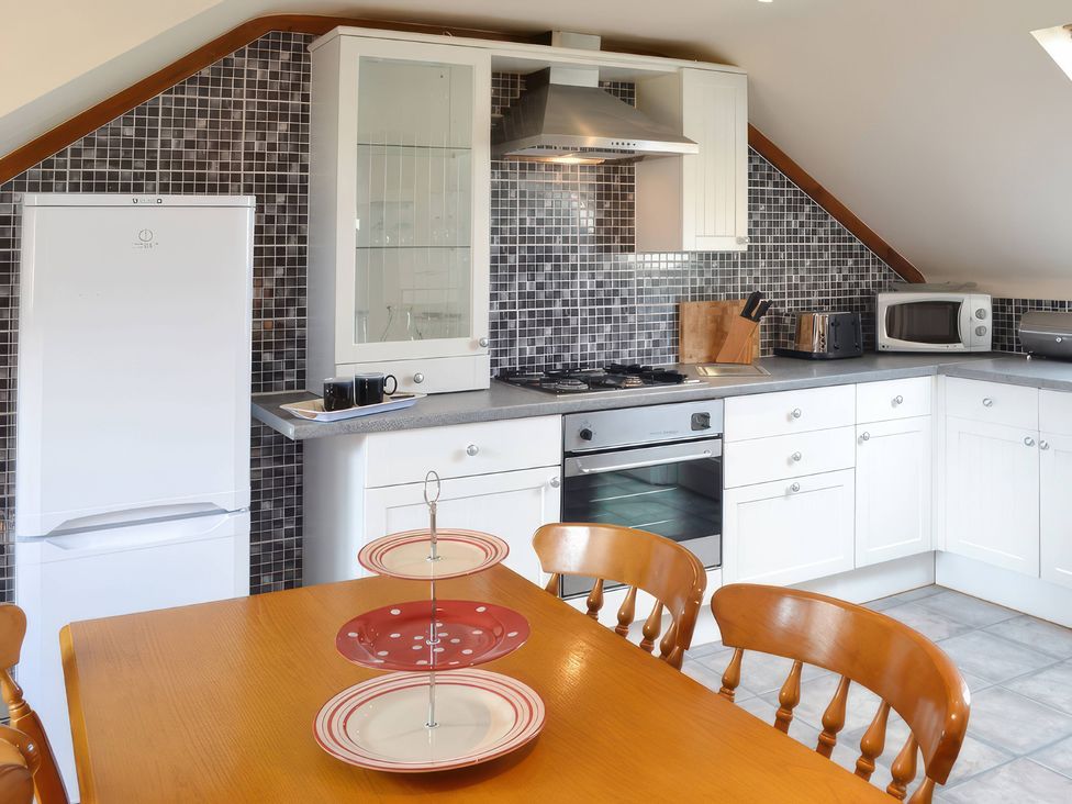 A kitchen with appliances and dining table at The Coach House Budock Water near Falmouth