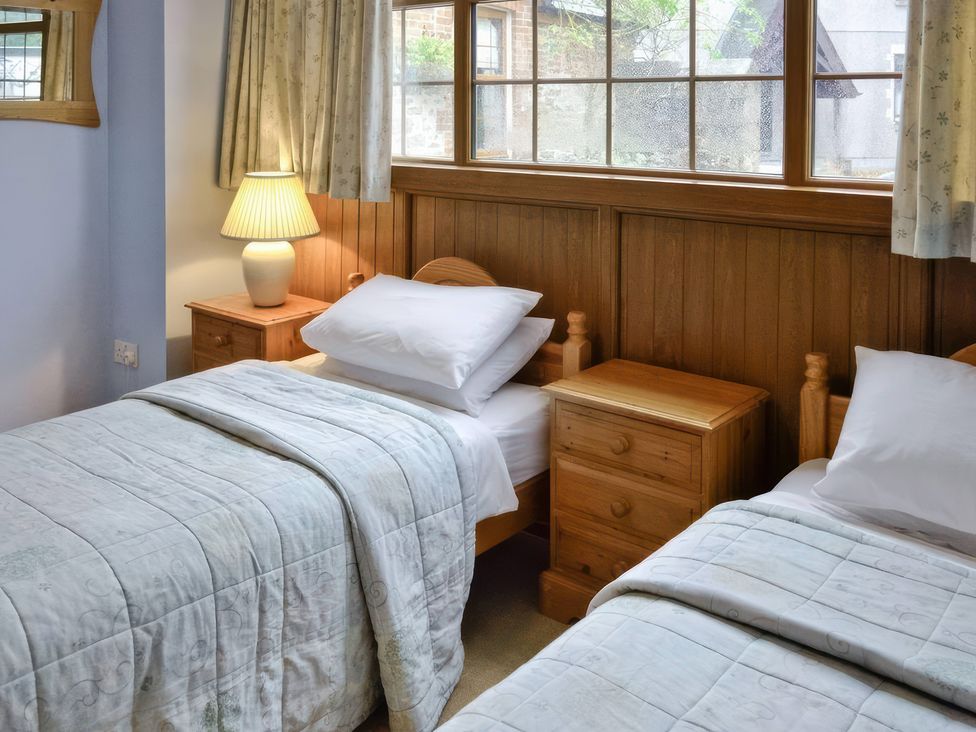 A bedroom with two beds and a nightstand at The Coach House Budock Water near Falmouth