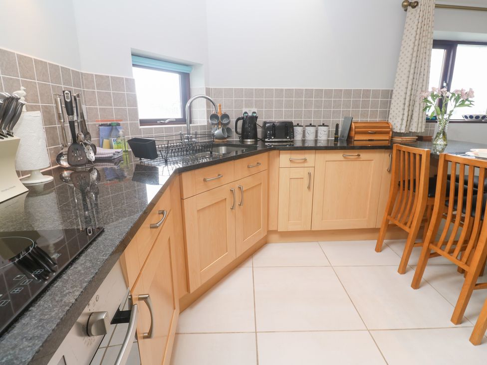 A kitchen with wooden cabinets and a dining table at Tobys Quay in Falmouth