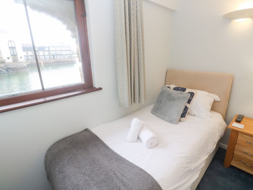 A bedroom with a bed and window overlooking the water at Tobys Quay in Falmouth
