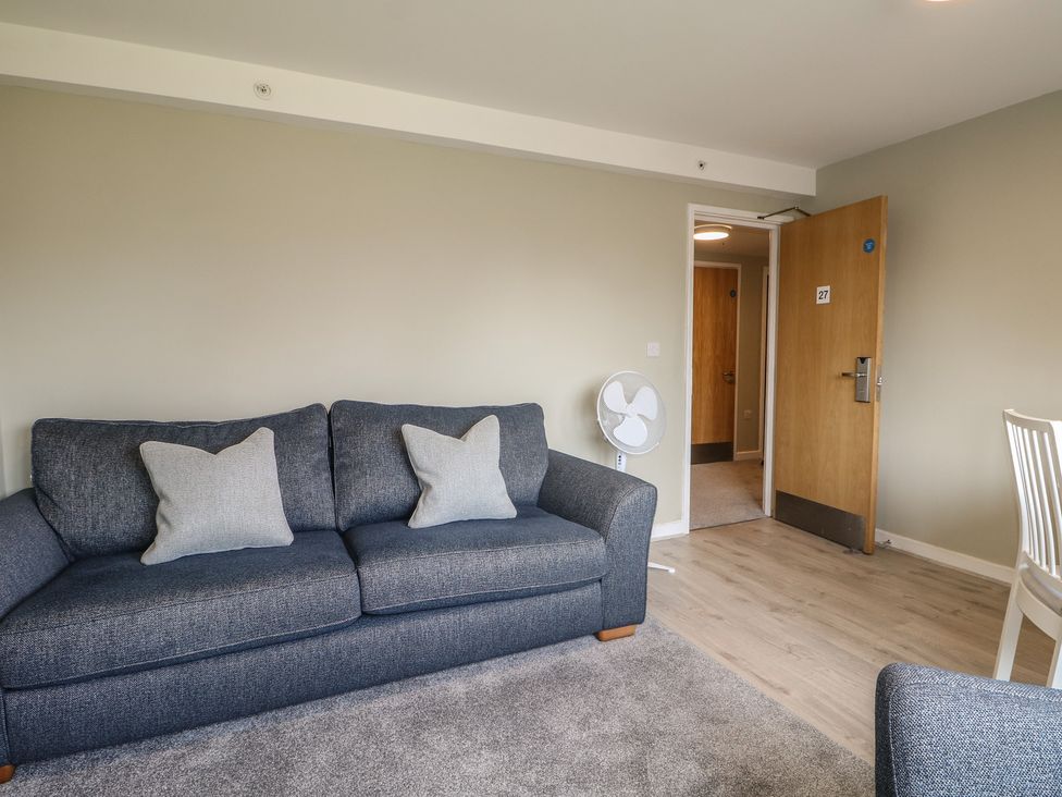 A living room with a sofa and fan at Flat 1 in Littlehampton