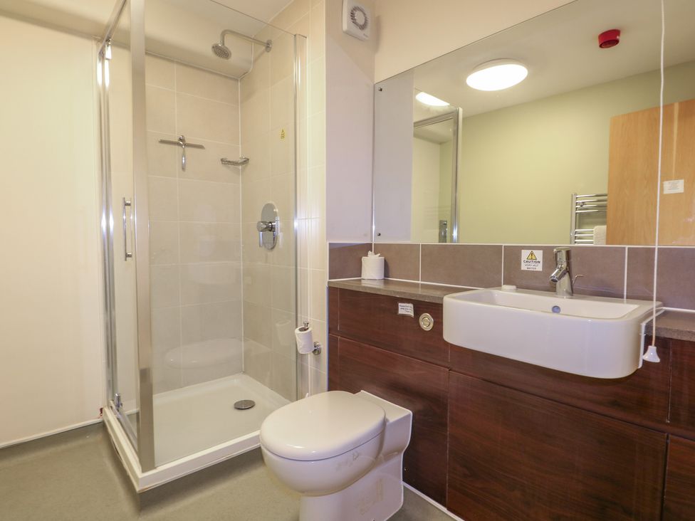 A bathroom with sink, toilet, shower, and mirror at Flat 1 in Littlehampton