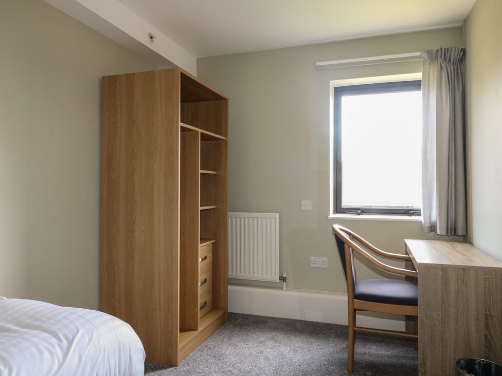 A bedroom with a wardrobe, desk, chair, and window at Flat 1 in Littlehampton
