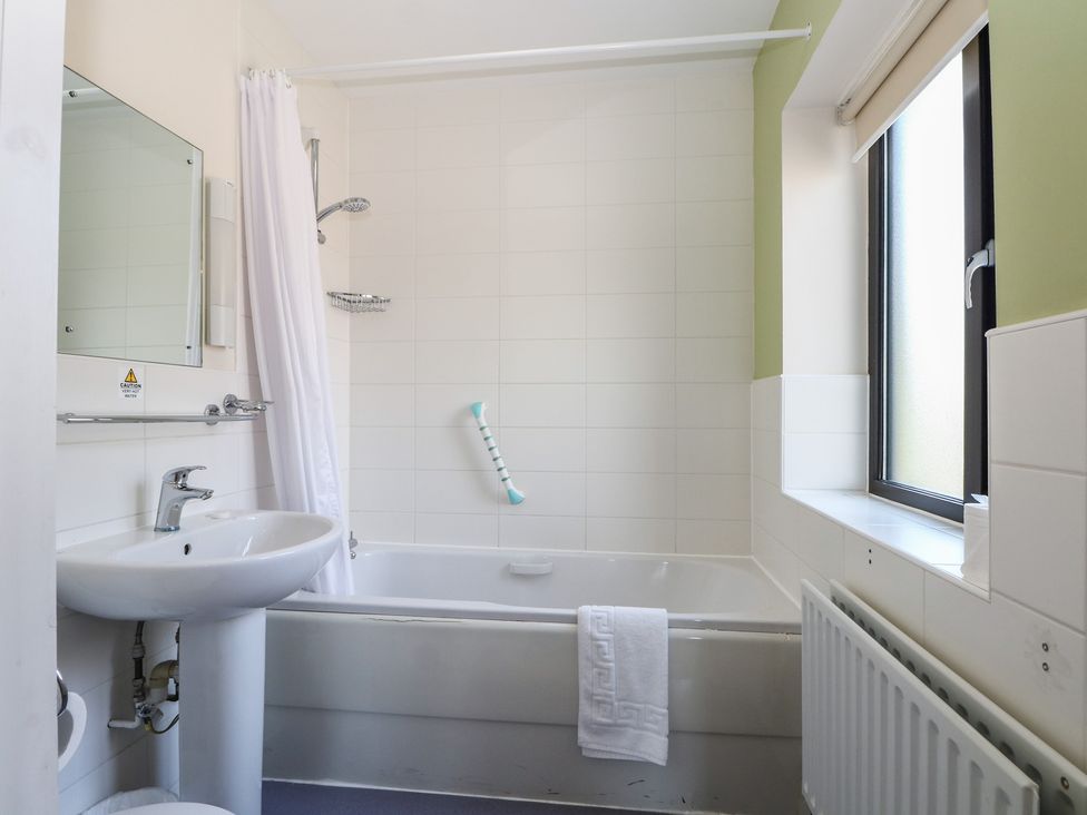 A bathroom with a bathtub and sink at Bedroom 10 in Littlehampton