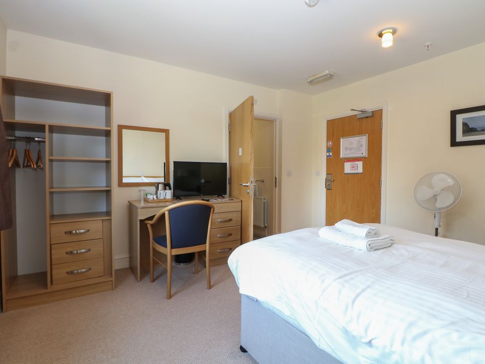 A bedroom with a bed, desk, and television at Bedroom 9 in Littlehampton