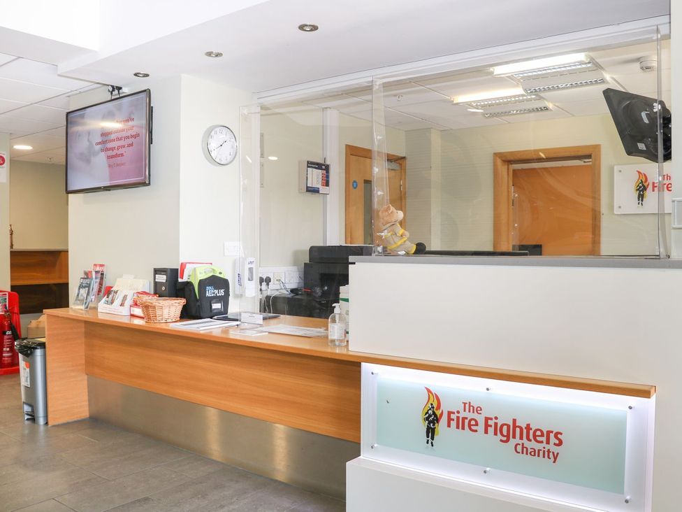A reception area with a desk and computer at The Fire Fighters Charity in Littlehampton
