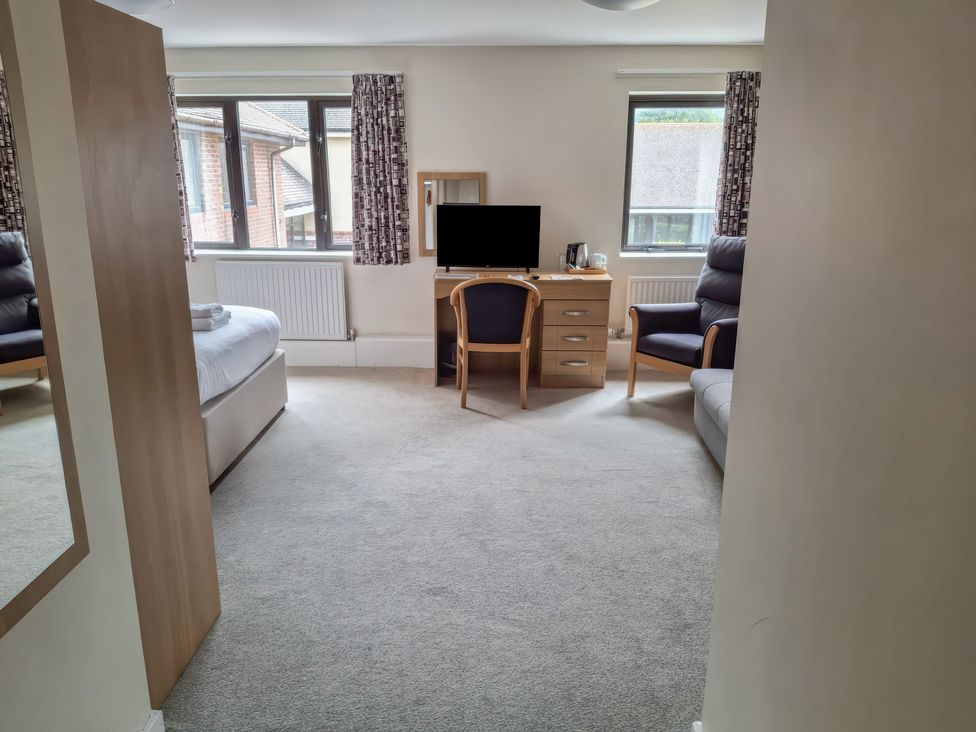 A bedroom with a bed, chair, TV, desk at The Driftwood Dwelling at Marine Court Littlehampton