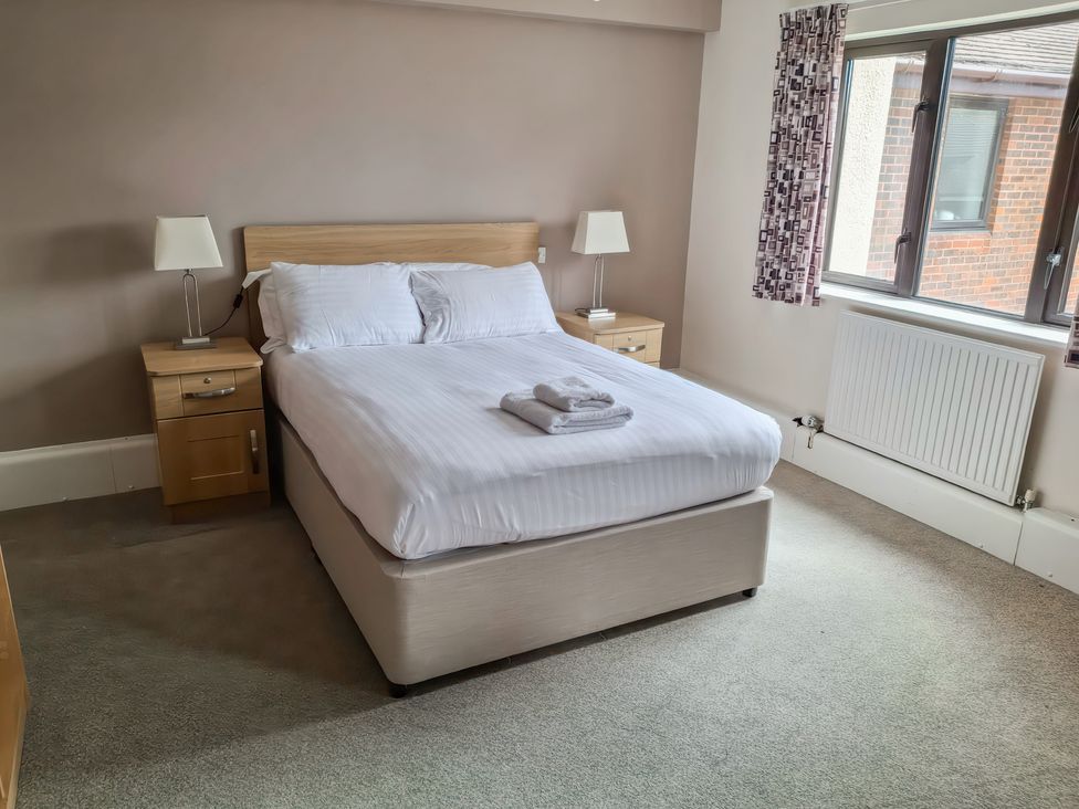 A bedroom with a bed and nightstands at The Driftwood Dwelling at Marine Court Littlehampton