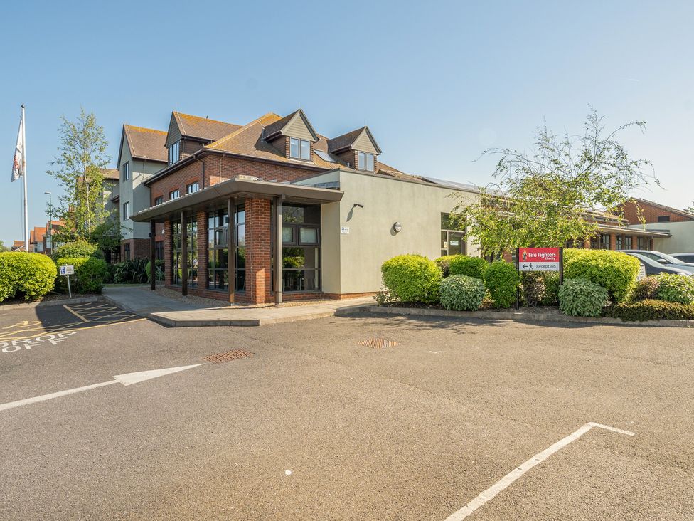 An exterior view of a building with trees and parking at Marine Court First-floor Double Bedroom with Wet Room in Littlehampton