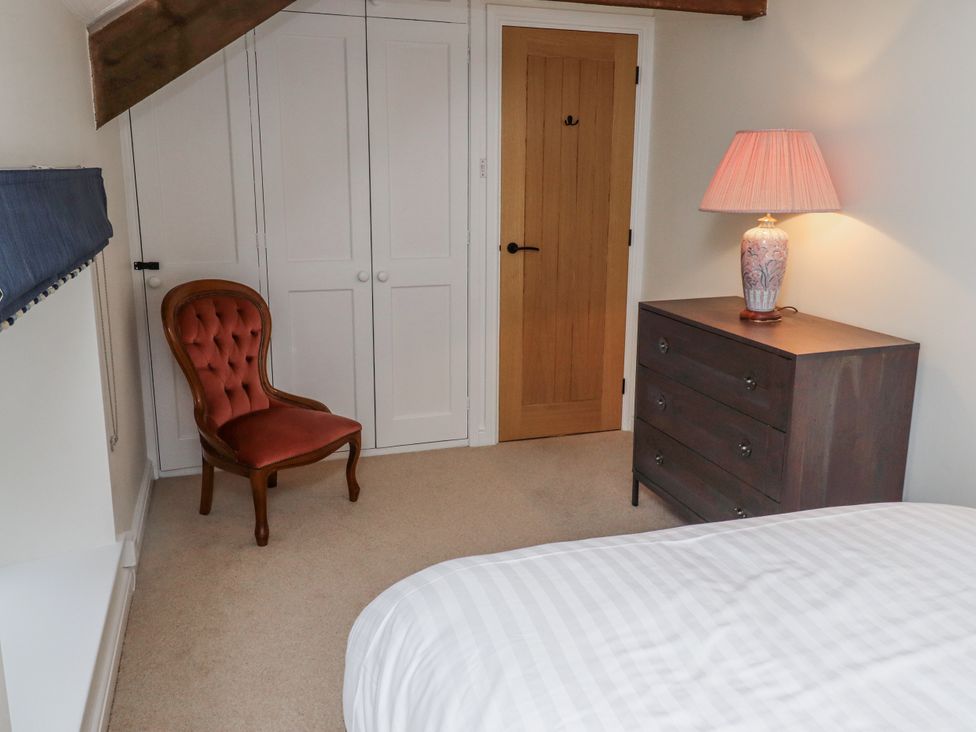 A bedroom with a chair, dresser, and lamp at 3 Christon Bank Mews in Alnwick