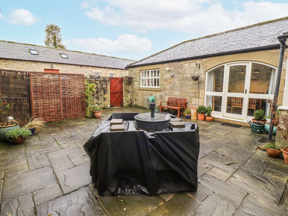 A garden with a fountain and potted plants at 3 Christon Bank Mews Alnwick