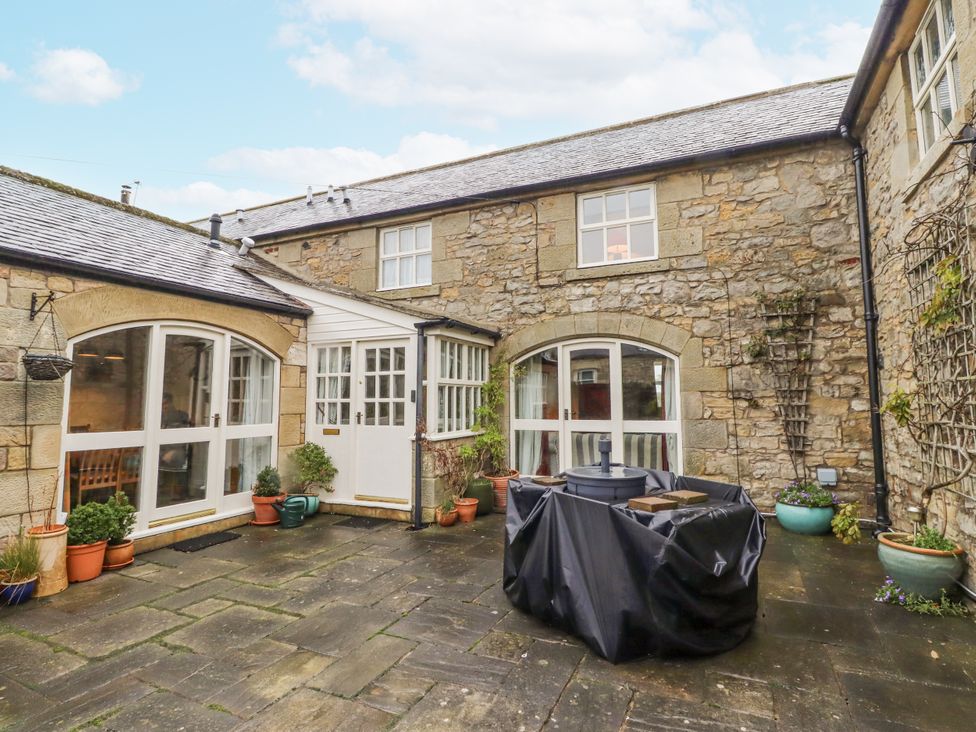 An outdoor area with stone walls and a patio at 3 Christon Bank Mews Alnwick