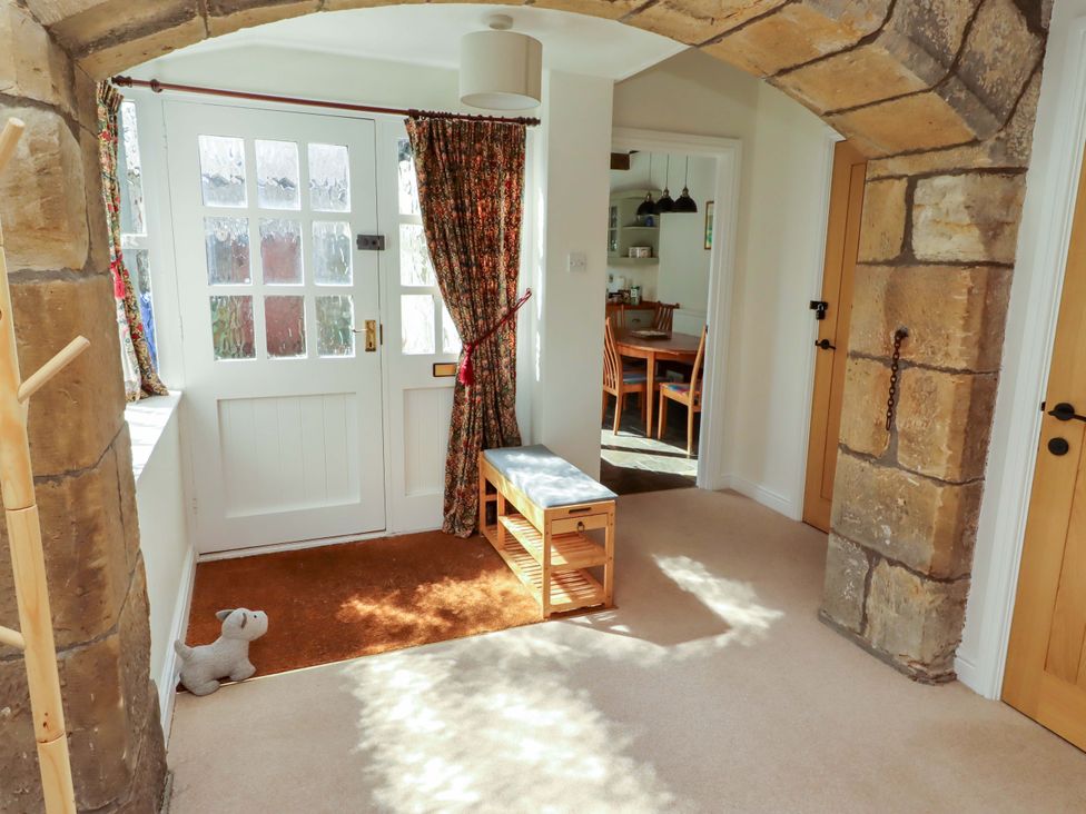A hallway with a bench and door at 3 Christon Bank Mews in Christon Bank