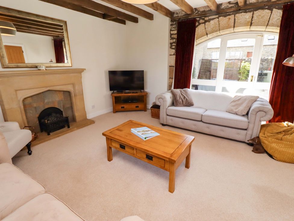 A living room with a sofa, coffee table, and television at 3 Christon Bank Mews, Christon Bank