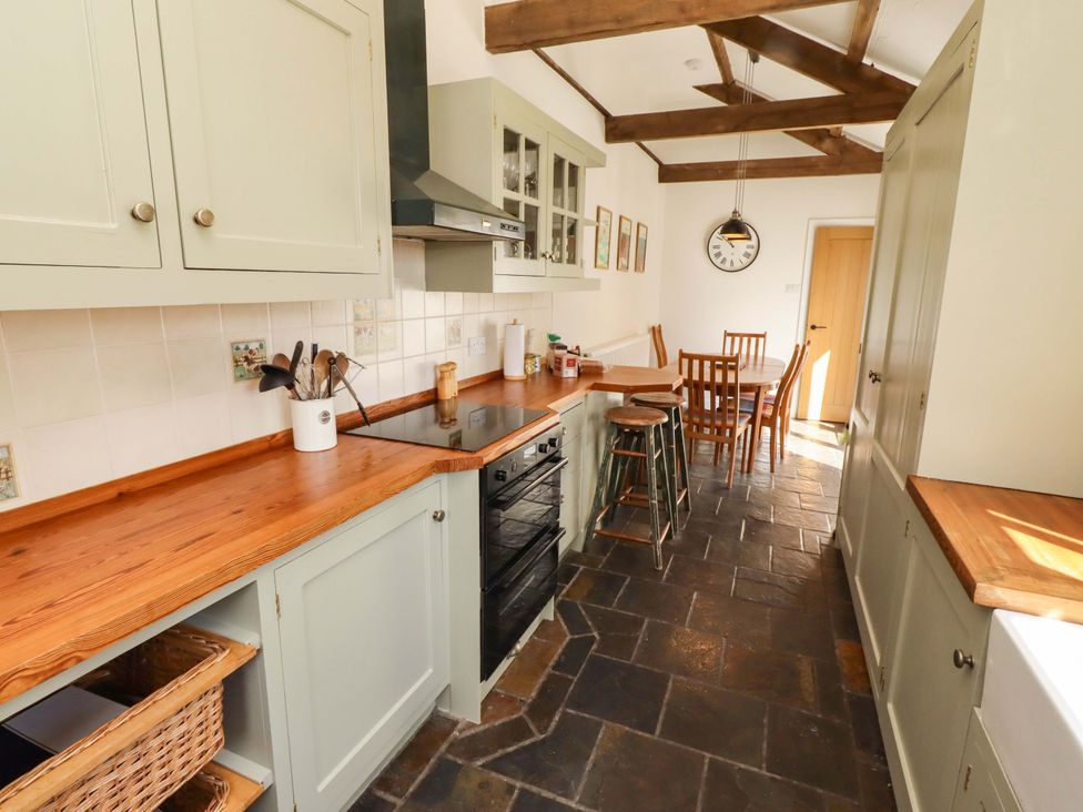 A kitchen with cabinets and a table with chairs at 3 Christon Bank Mews Christon Bank