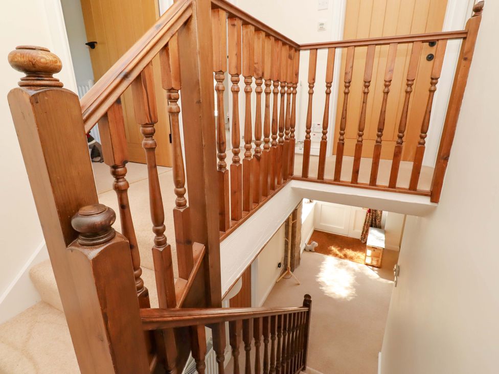 A staircase with wooden banister and door at 3 Christon Bank Mews Christon Bank