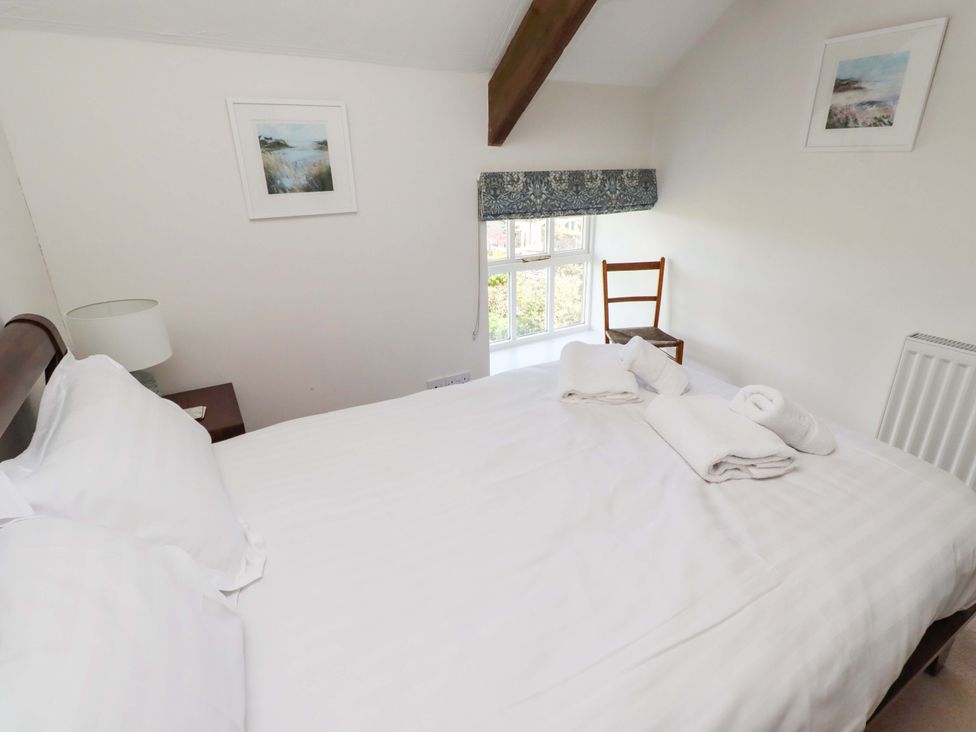 A bedroom with a bed and a chair at 3 Christon Bank Mews in Christon Bank
