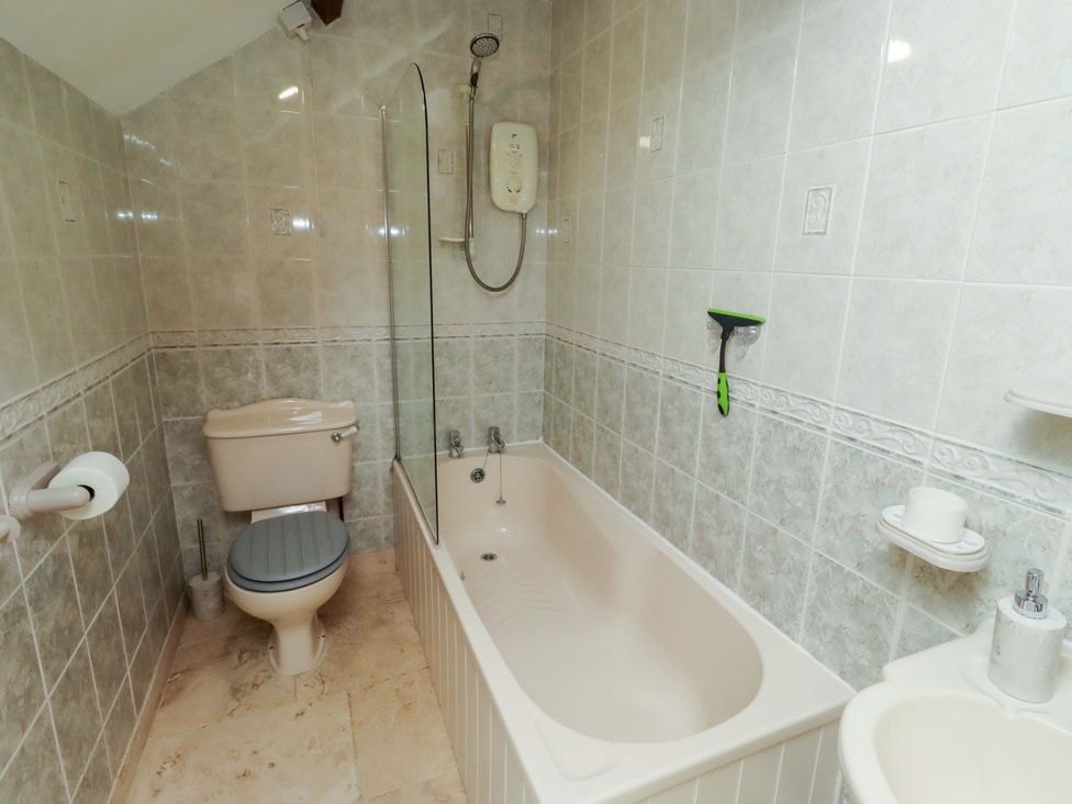 A bathroom with a bathtub, shower, sink, and toilet at 3 Christon Bank Mews in Christon Bank