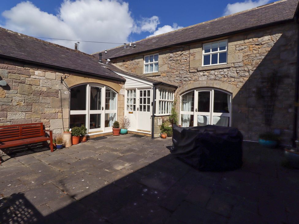 An outdoor area with a bench and stone walls at 3 Christon Bank Mews in Christon Bank
