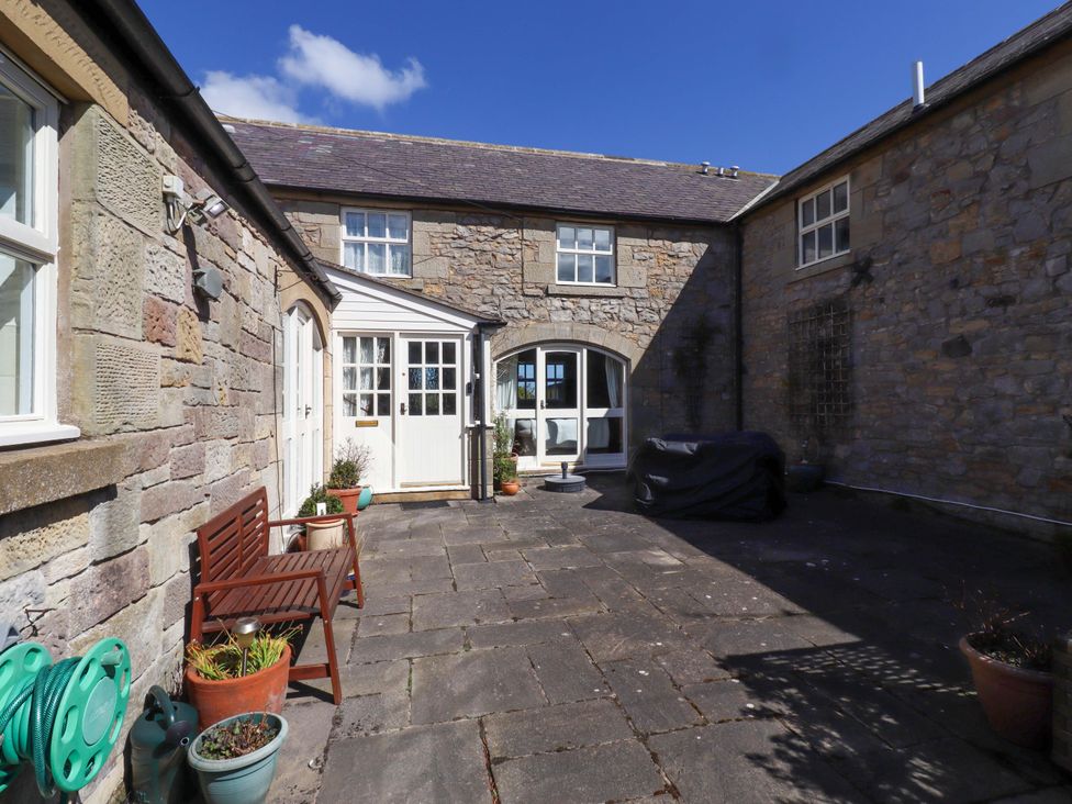 An outdoor area with a stone wall, glass doors, and seating at 3 Christon Bank Mews Christon Bank