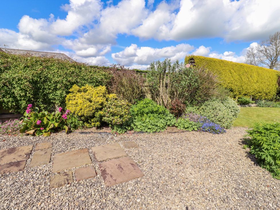 A garden with a flower bed and gravel pathway at 3 Christon Bank Mews Christon Bank