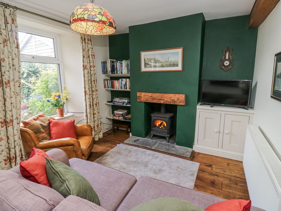 A living room with a fireplace and bookshelf at Centenary Cottage in Skipton