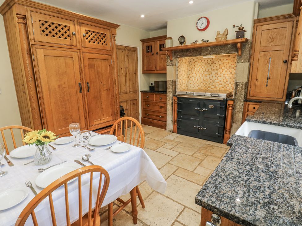 A kitchen with a dining table and wooden cupboards at Centenary Cottage in Skipton
