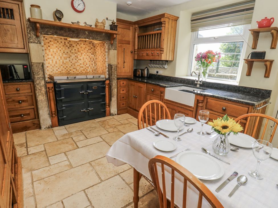 A kitchen with a dining table and stove at Centenary Cottage, Skipton