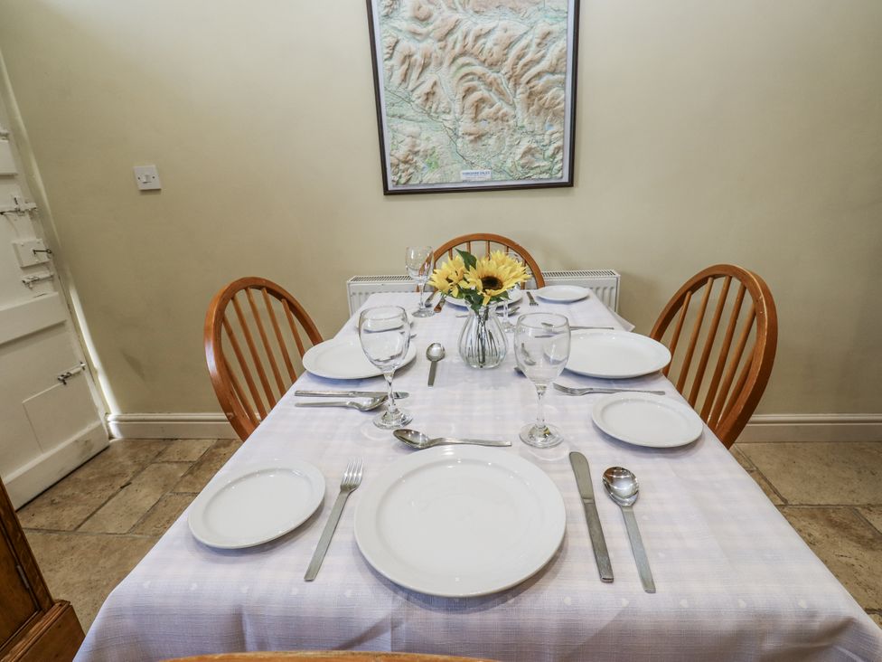 A dining room with a table set for meals at Centenary Cottage in Skipton