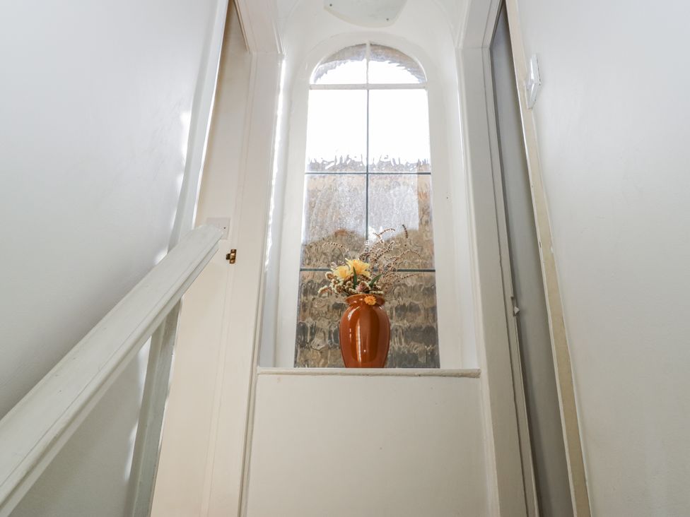 A staircase leading up to a vase on a ledge in Centenary Cottage Skipton