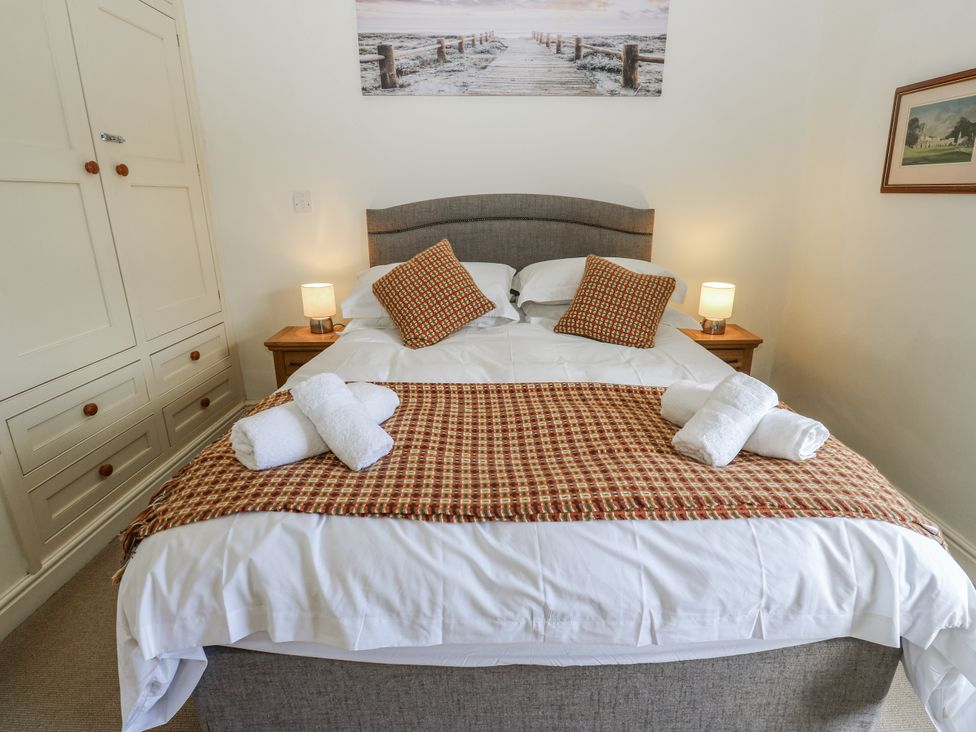 A bedroom with a bed and wardrobe at Centenary Cottage in Skipton