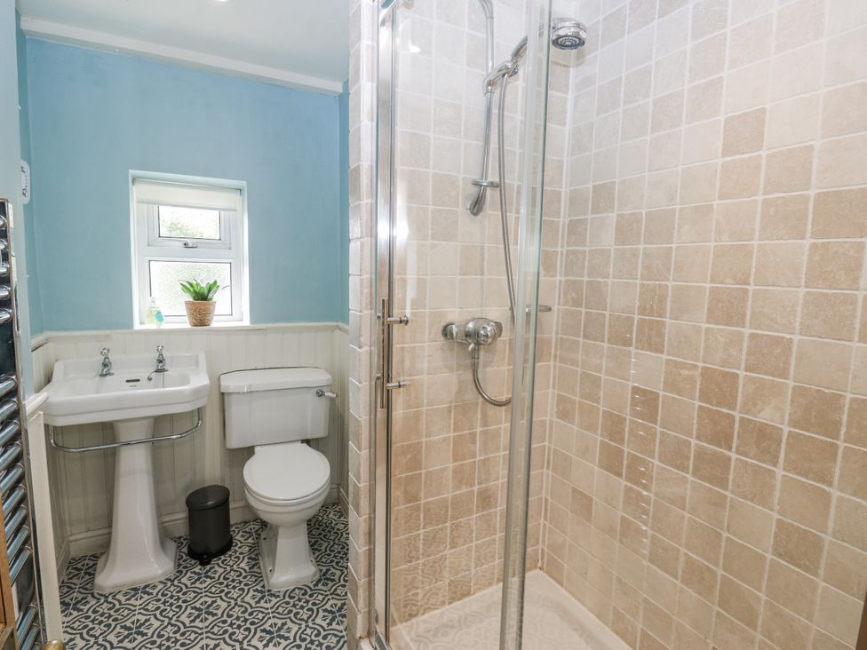 A bathroom with a sink, toilet, and shower at Centenary Cottage in Skipton