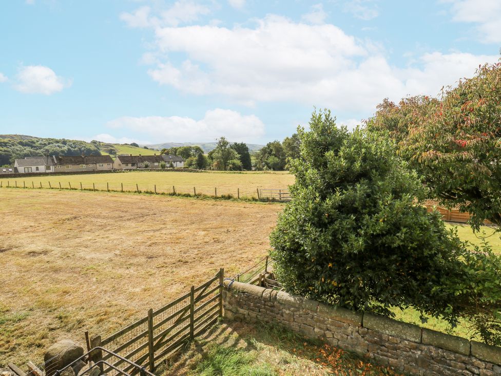 A field with a fence and trees in the background at Centenary Cottage in Skipton