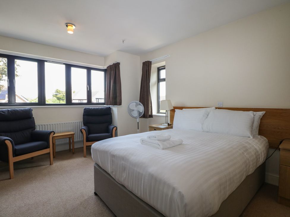 A bedroom with a bed and two chairs at Bedroom 18 in Littlehampton