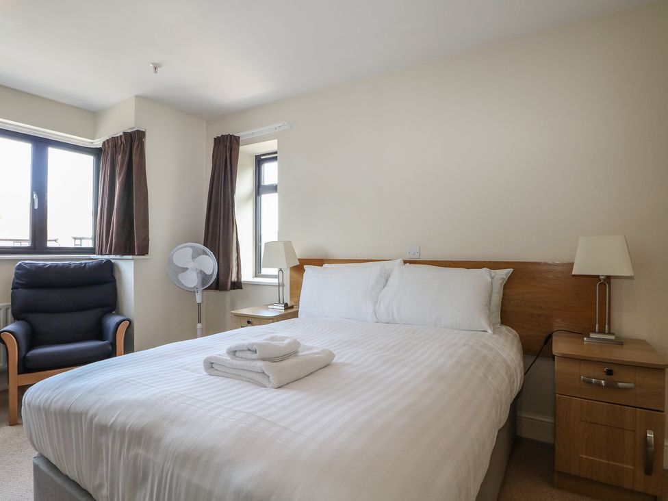 A bedroom with a bed and an armchair at Bedroom 18 in Littlehampton