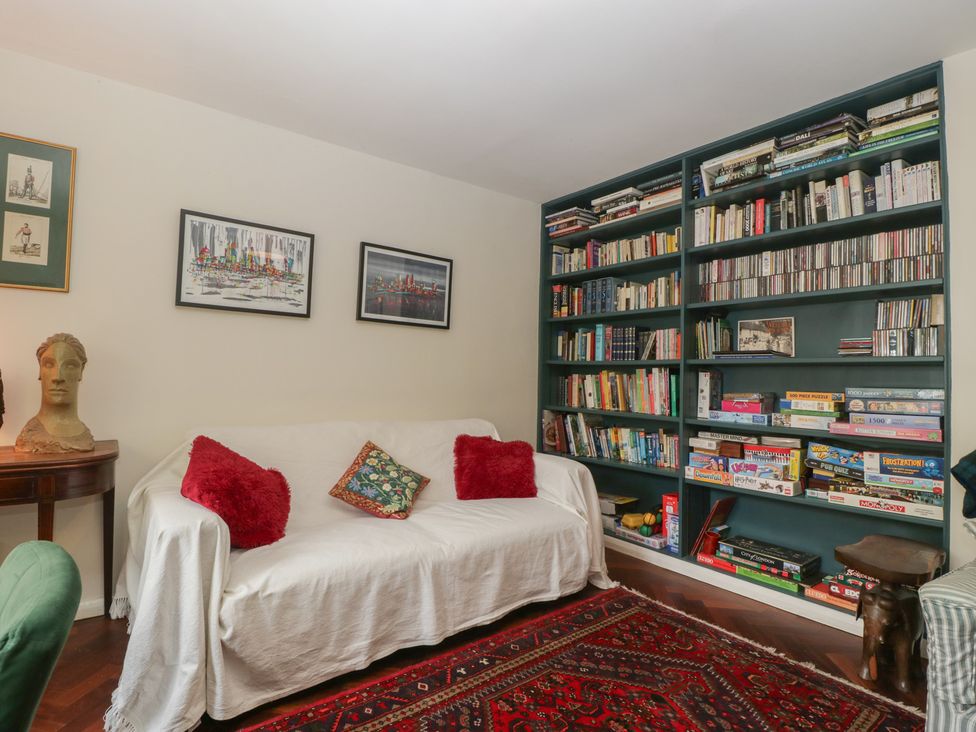A living room with a sofa and bookshelf at St. Marys House in Church Westcote near Bledington