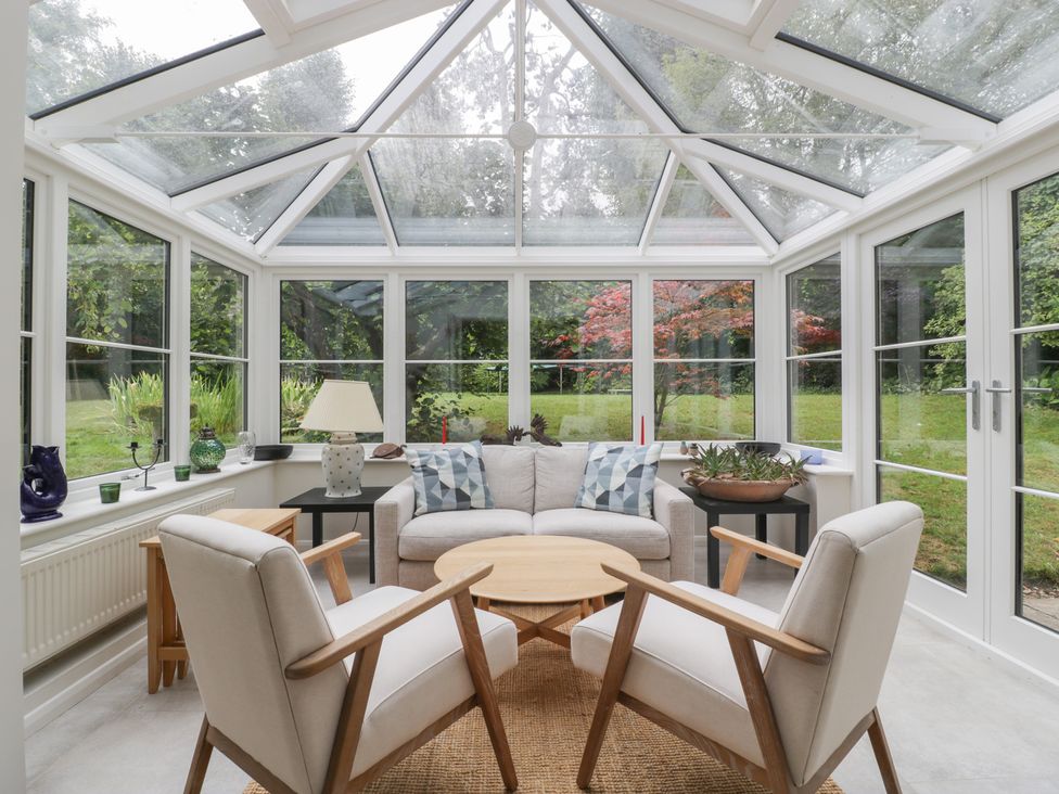A conservatory with seating and plants at St. Marys House, Church Westcote near Bledington